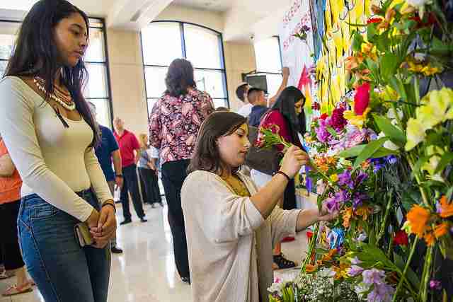 Students and faculty lay flowers at a remembrance wall during the Osceola Campus vigil.