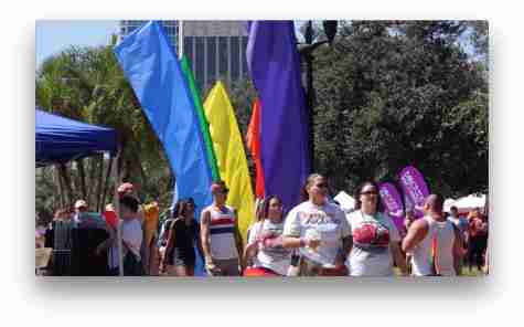 marchers in front of rainbow flags at Come Out With Pride event