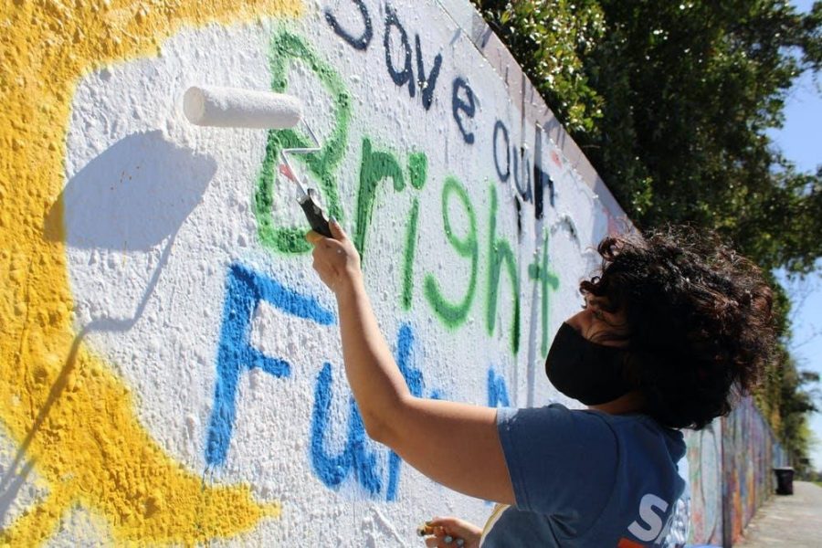 Alondra Arce, 20, a UF sustainability sophomore, paints a mural that says Save Our Bright Futures on Sunday, March 7, 2021. Arce recruited student volunteers to help her create the mural along 34th Street in Gainesville to raise awareness about Senate Bill 86, which would limit some students access to state funding for college if passed.
