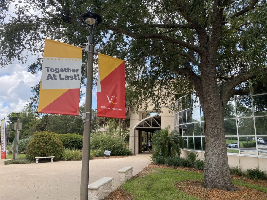 Flags read "Valencia College" and "Together At Last" along a campus road. 