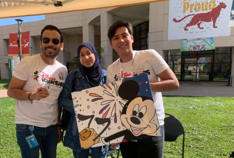 Reporter Aya Anzouk poses alongside East Campus students and Mickey Mouse art work. 