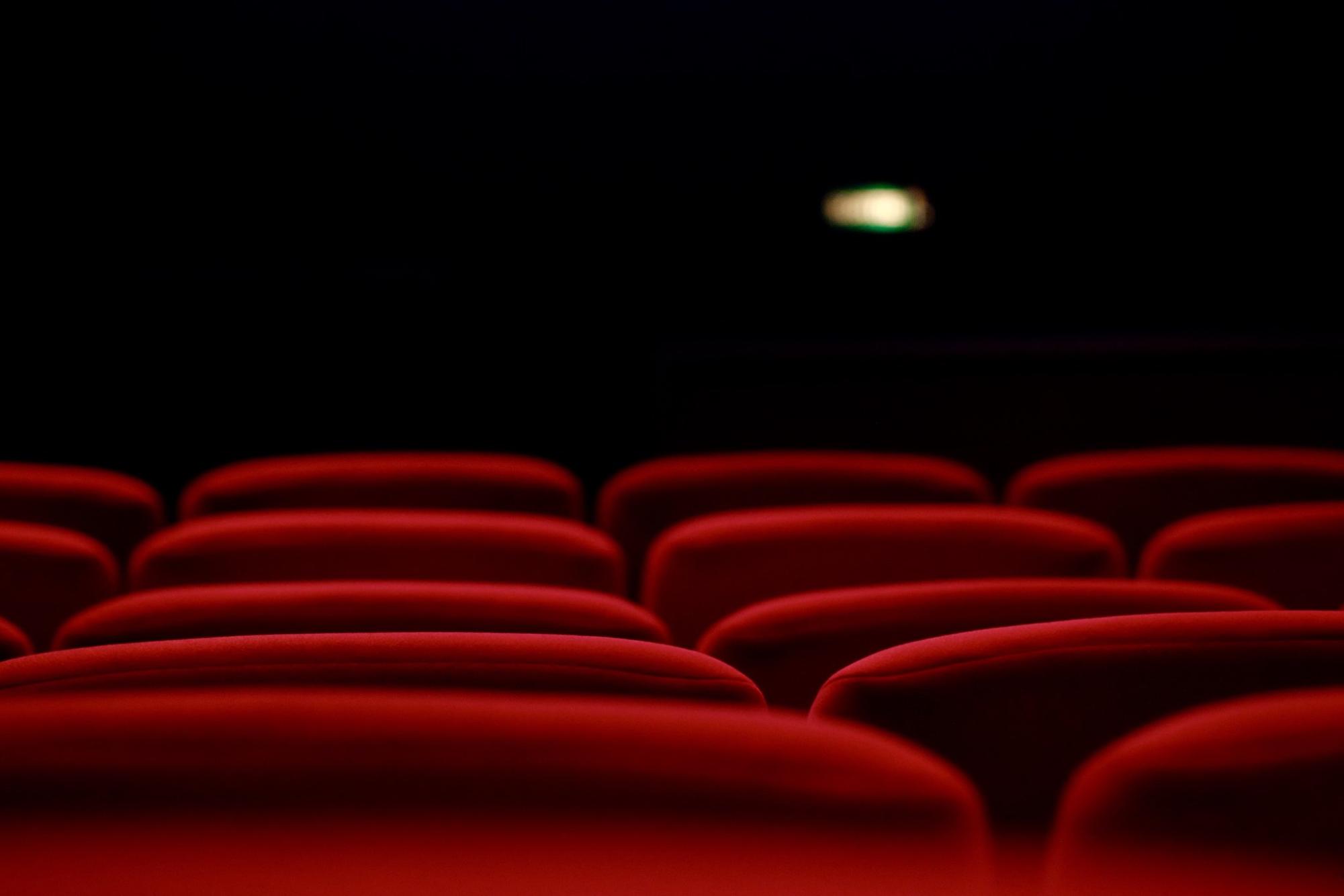Closeup of red seats under the lights in a cinema in Switzerland. Image provided with Attribution by user wirestock on Freepik.com.